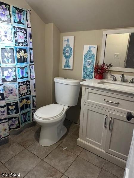 bathroom featuring tile patterned flooring, vaulted ceiling, vanity, and toilet