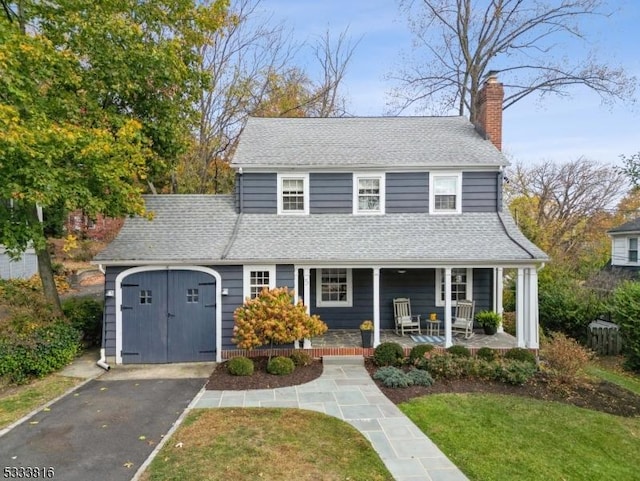 view of front of home with a garage, covered porch, and a front lawn