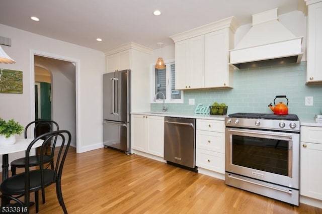 kitchen featuring sink, light hardwood / wood-style flooring, appliances with stainless steel finishes, white cabinets, and custom exhaust hood