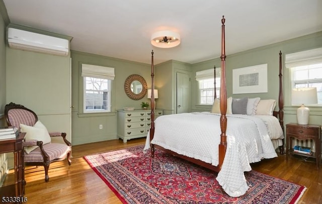 bedroom featuring ornamental molding, a wall mounted AC, and hardwood / wood-style floors