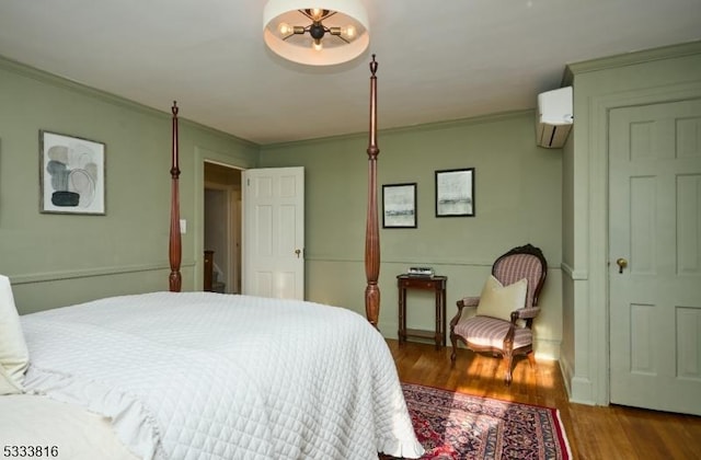 bedroom with hardwood / wood-style flooring, ornamental molding, and a wall unit AC