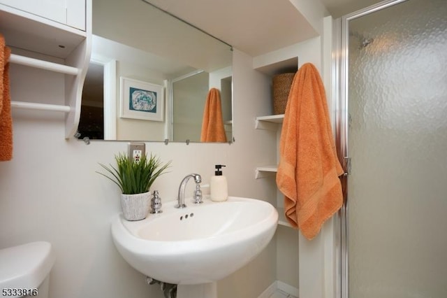 bathroom with sink, an enclosed shower, and toilet