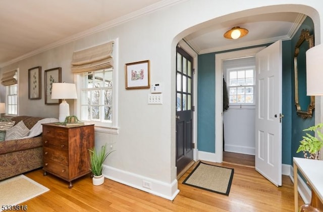 foyer with ornamental molding and light hardwood / wood-style floors