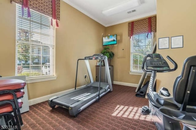 exercise room with ornamental molding, visible vents, dark carpet, and baseboards