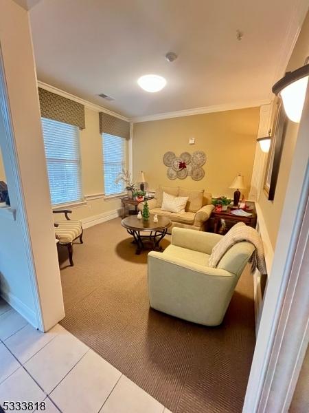 living room featuring light carpet, light tile patterned floors, baseboards, and crown molding