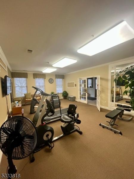 workout area with baseboards, visible vents, crown molding, and carpet flooring