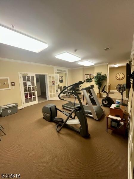 exercise room with carpet floors, visible vents, and crown molding