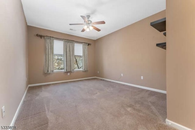 spare room featuring carpet floors, ceiling fan, and baseboards