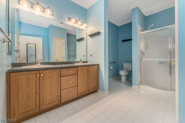 full bathroom featuring double vanity, a stall shower, toilet, tile patterned floors, and a sink