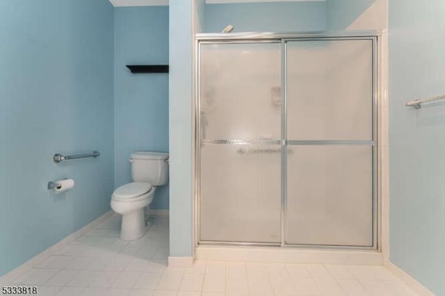 full bath with toilet, a stall shower, and baseboards