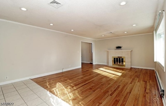 unfurnished living room featuring crown molding, a baseboard heating unit, a high end fireplace, and light hardwood / wood-style floors