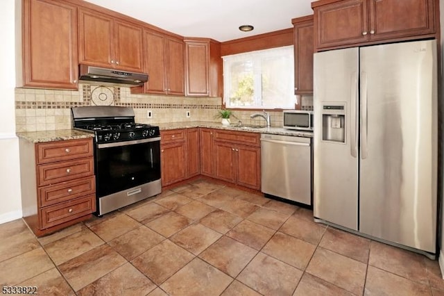 kitchen featuring appliances with stainless steel finishes, sink, backsplash, and light stone counters