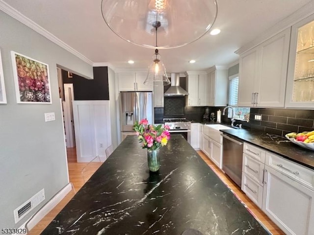 kitchen with white cabinetry, sink, wall chimney range hood, and stainless steel appliances