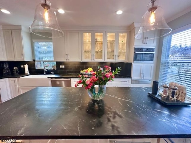 kitchen with appliances with stainless steel finishes, dark stone counters, pendant lighting, white cabinets, and sink