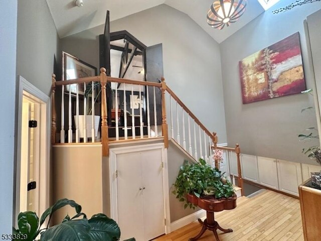 stairs with vaulted ceiling and wood-type flooring