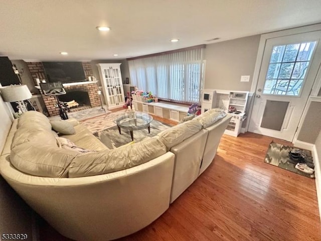 living room featuring a brick fireplace and light hardwood / wood-style flooring