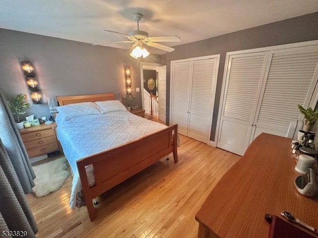 bedroom featuring ceiling fan, light hardwood / wood-style floors, and multiple closets