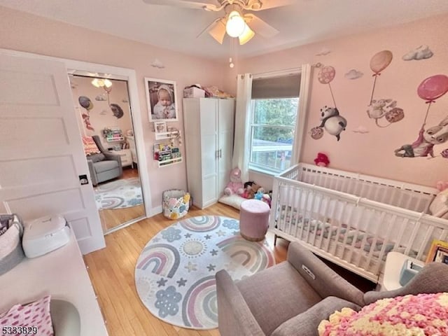 bedroom with ceiling fan, light hardwood / wood-style flooring, and a crib