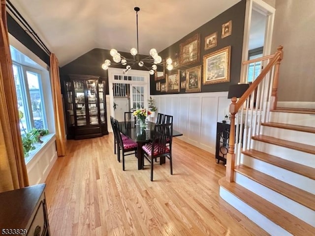 dining space featuring lofted ceiling, a notable chandelier, and light hardwood / wood-style floors