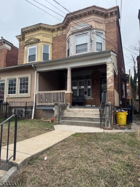 italianate-style house with covered porch and a front lawn