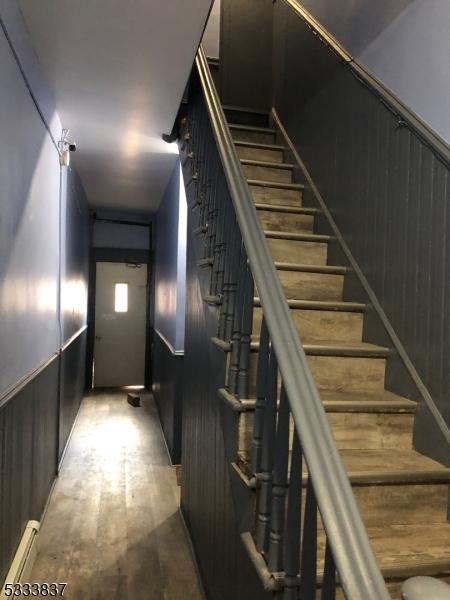 stairs with wood walls, a baseboard heating unit, and hardwood / wood-style floors