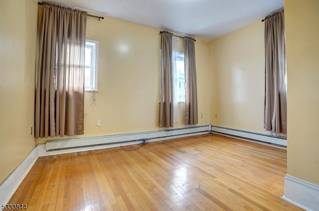 spare room featuring a baseboard radiator and light hardwood / wood-style floors