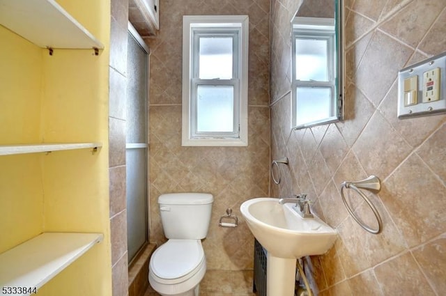 bathroom with toilet, an enclosed shower, and tile walls