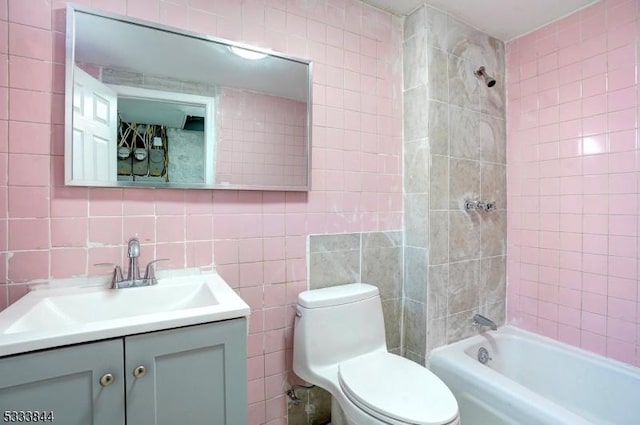 full bathroom with tile walls, vanity, tiled shower / bath combo, and toilet