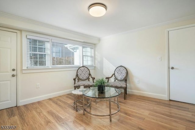 sitting room with ornamental molding and light hardwood / wood-style flooring