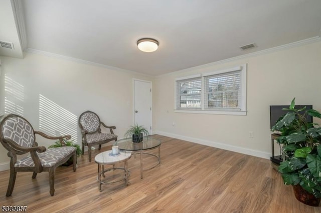 living area with crown molding and light hardwood / wood-style flooring