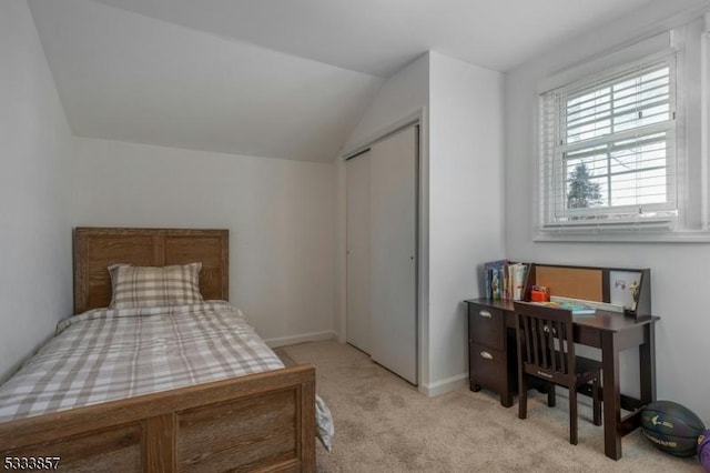 bedroom featuring vaulted ceiling, light carpet, and a closet