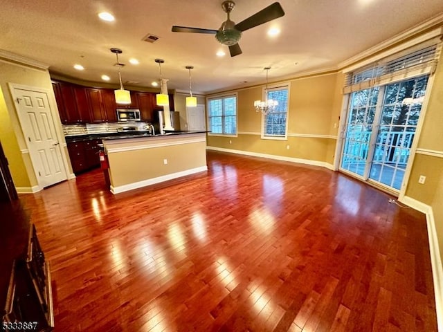 kitchen featuring dark hardwood / wood-style floors, ceiling fan with notable chandelier, decorative light fixtures, a kitchen island with sink, and crown molding