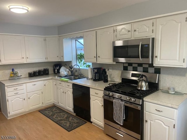 kitchen featuring light hardwood / wood-style flooring, sink, white cabinets, decorative backsplash, and stainless steel appliances