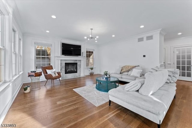 living room featuring dark wood-type flooring, ornamental molding, a chandelier, and a fireplace