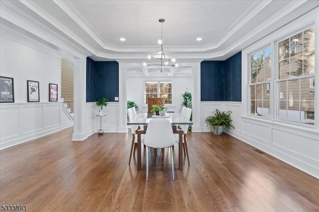 dining room with hardwood / wood-style flooring, ornamental molding, a raised ceiling, and a notable chandelier