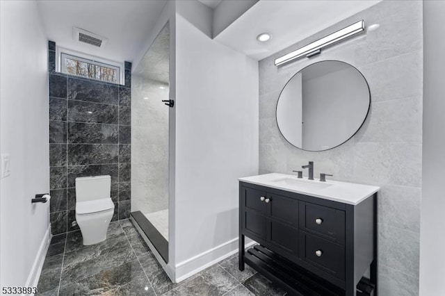 bathroom with walk in shower, toilet, vanity, and tile walls