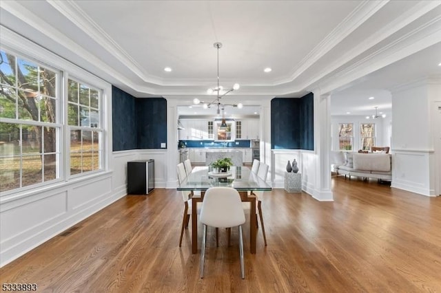 dining area featuring hardwood / wood-style flooring, a tray ceiling, crown molding, and an inviting chandelier