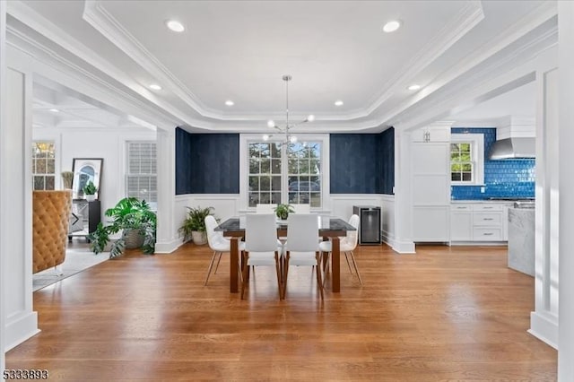 dining room featuring a healthy amount of sunlight, light hardwood / wood-style flooring, and a tray ceiling