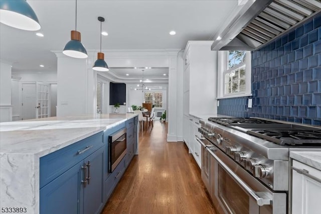 kitchen featuring appliances with stainless steel finishes, decorative light fixtures, premium range hood, white cabinets, and decorative backsplash