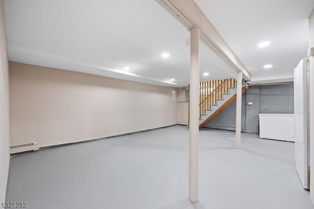 basement with white refrigerator and a baseboard radiator