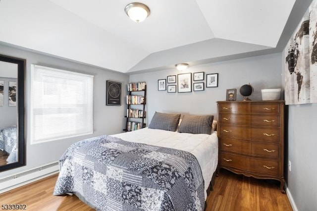 bedroom with vaulted ceiling, wood-type flooring, and a baseboard heating unit