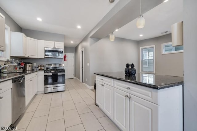 kitchen with sink, white cabinetry, dark stone countertops, appliances with stainless steel finishes, and pendant lighting