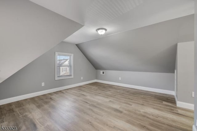 additional living space featuring vaulted ceiling and light hardwood / wood-style flooring