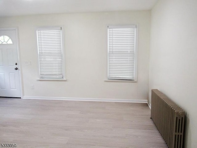 foyer entrance featuring radiator heating unit, light wood-type flooring, and baseboards