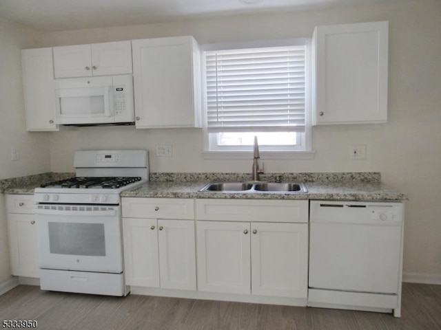 kitchen with white appliances, a sink, white cabinets, and light wood finished floors