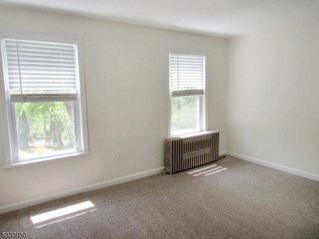 empty room featuring radiator heating unit, carpet flooring, and baseboards