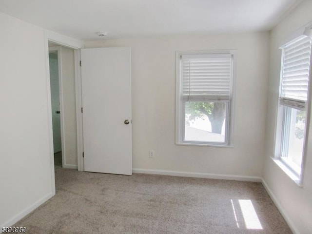 carpeted empty room featuring baseboards