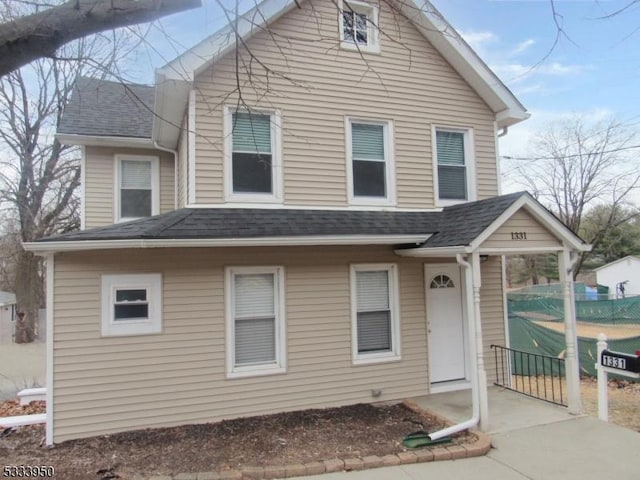 view of front of home with a shingled roof and fence