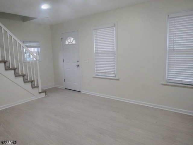 entryway with stairs, baseboards, and wood finished floors