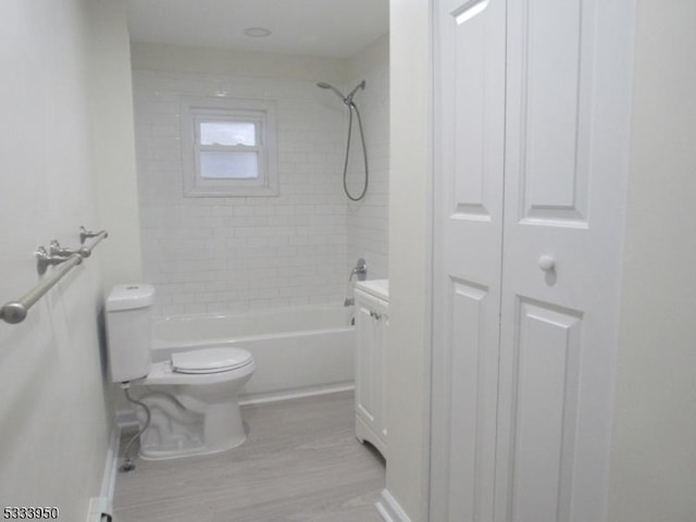full bath featuring toilet, washtub / shower combination, a closet, wood finished floors, and baseboards